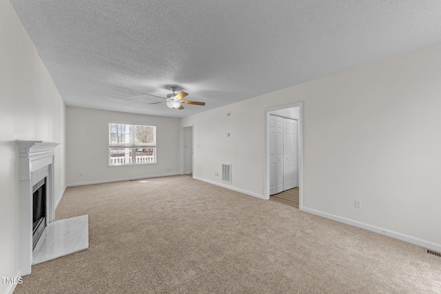 unfurnished living room featuring visible vents, baseboards, ceiling fan, carpet floors, and a fireplace