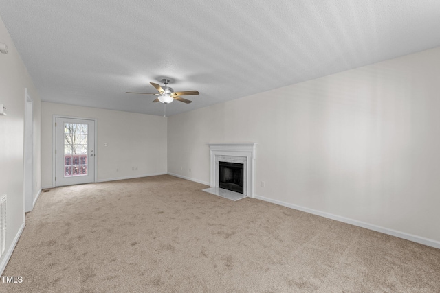 unfurnished living room with baseboards, a ceiling fan, a fireplace with flush hearth, a textured ceiling, and carpet floors