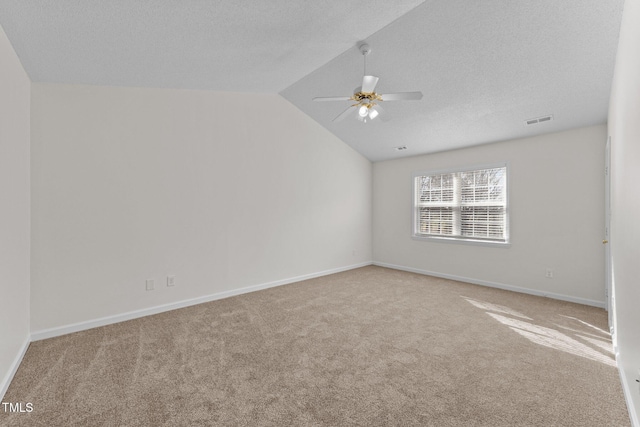 spare room featuring carpet, lofted ceiling, a ceiling fan, a textured ceiling, and baseboards