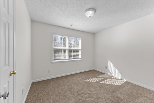 carpeted spare room with a textured ceiling, visible vents, and baseboards