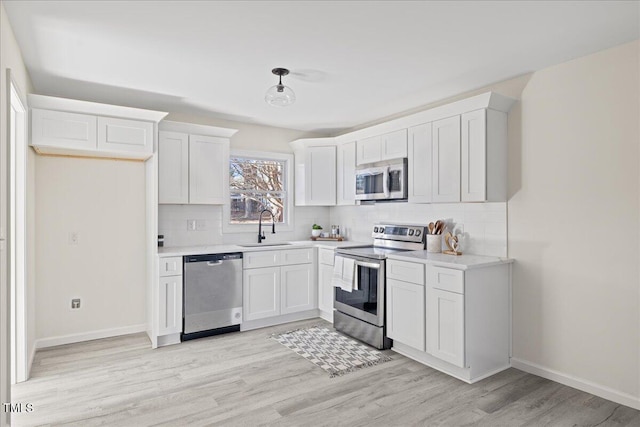 kitchen featuring sink, light hardwood / wood-style flooring, appliances with stainless steel finishes, tasteful backsplash, and white cabinetry