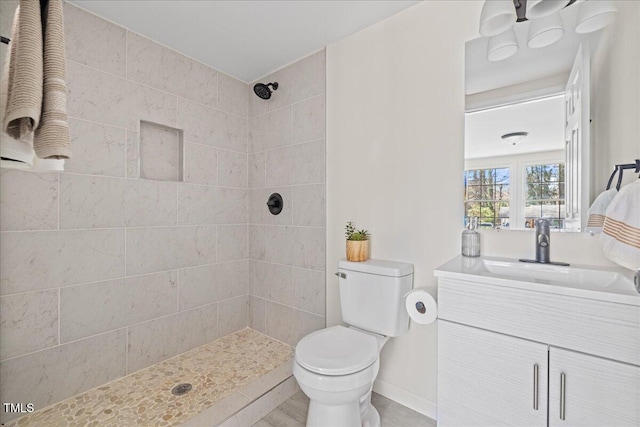 bathroom featuring toilet, vanity, and tiled shower