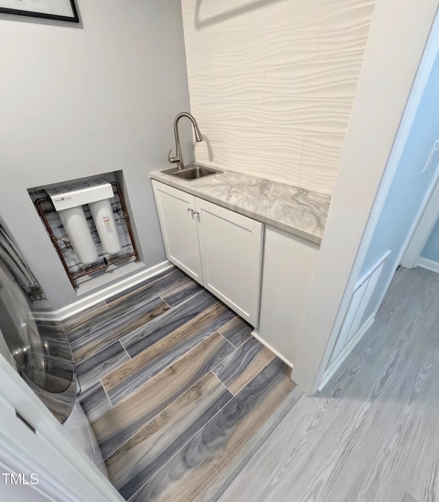 bar with white cabinets, light stone countertops, and sink