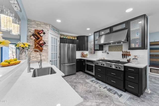 kitchen featuring decorative backsplash, sink, light stone counters, and appliances with stainless steel finishes