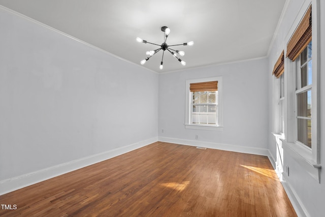 unfurnished room featuring wood-type flooring, crown molding, and a chandelier