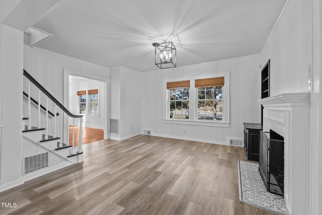 unfurnished living room featuring a chandelier and light hardwood / wood-style floors