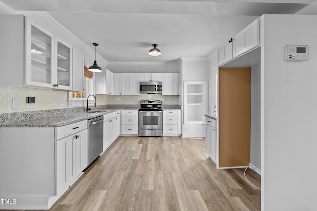 kitchen featuring stainless steel appliances, sink, pendant lighting, white cabinets, and light hardwood / wood-style floors