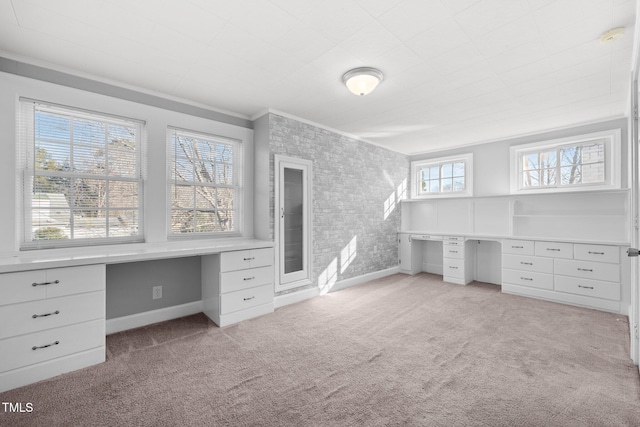 unfurnished office featuring built in desk, plenty of natural light, and crown molding