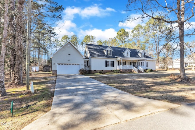 cape cod-style house with a porch, a garage, and an outdoor structure