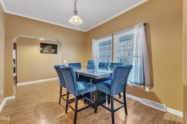 dining area with light wood-type flooring and ornamental molding