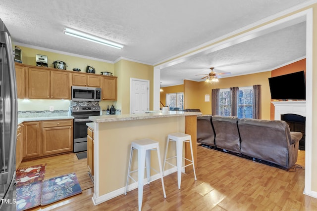 kitchen with a kitchen island, light hardwood / wood-style floors, a textured ceiling, and appliances with stainless steel finishes