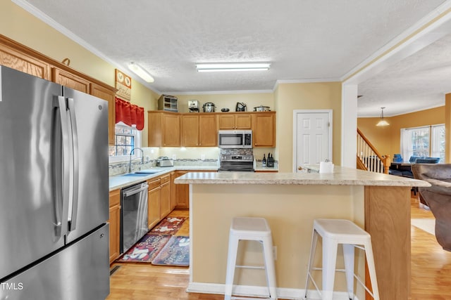 kitchen with sink, a kitchen island, a textured ceiling, and appliances with stainless steel finishes