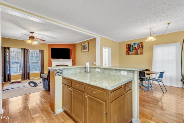 kitchen featuring ceiling fan, light wood-type flooring, ornamental molding, and a textured ceiling