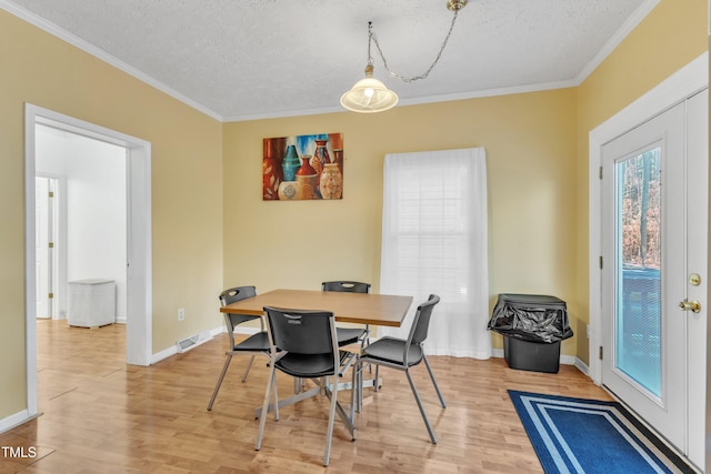 dining area with a textured ceiling, light hardwood / wood-style flooring, and ornamental molding