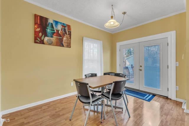 dining area featuring light hardwood / wood-style floors, ornamental molding, a textured ceiling, and french doors