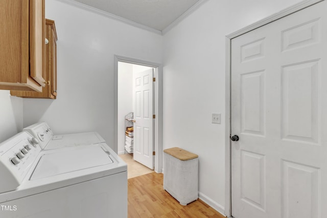 clothes washing area with crown molding, washer and clothes dryer, cabinets, and light wood-type flooring