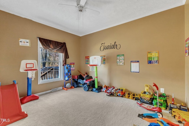 playroom with ceiling fan, carpet floors, a textured ceiling, and ornamental molding