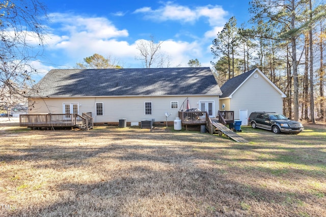 rear view of property with central air condition unit, a wooden deck, french doors, and a lawn