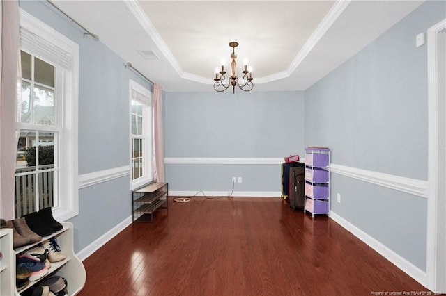 interior space featuring dark hardwood / wood-style flooring, an inviting chandelier, a raised ceiling, and crown molding