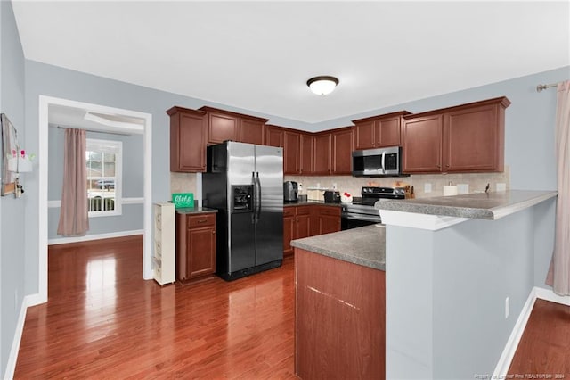 kitchen with hardwood / wood-style flooring, decorative backsplash, and appliances with stainless steel finishes