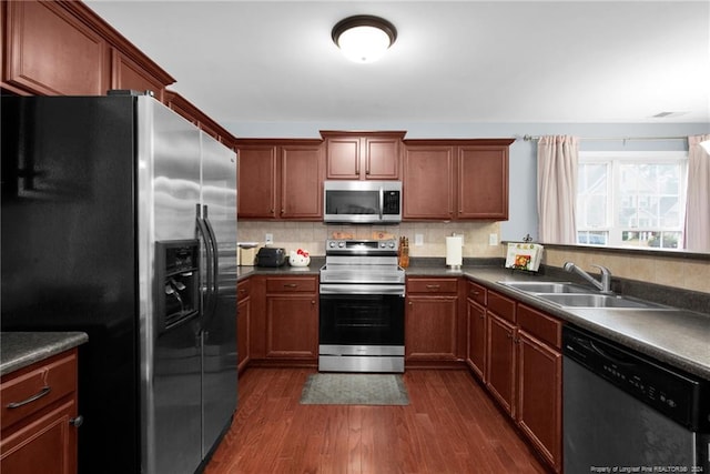 kitchen featuring dark wood-type flooring, decorative backsplash, sink, and stainless steel appliances