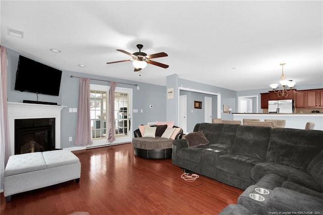 living room with ceiling fan with notable chandelier and wood-type flooring