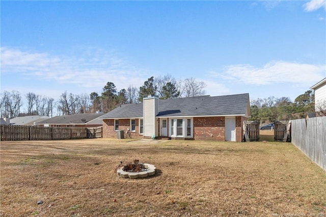 rear view of property with a yard and a fire pit