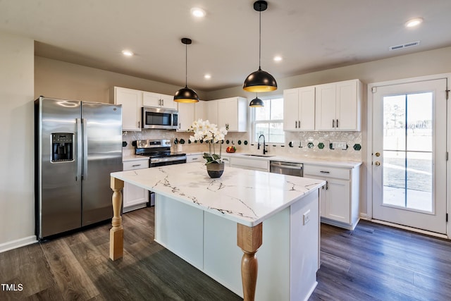 kitchen featuring sink, a center island, decorative light fixtures, white cabinets, and appliances with stainless steel finishes