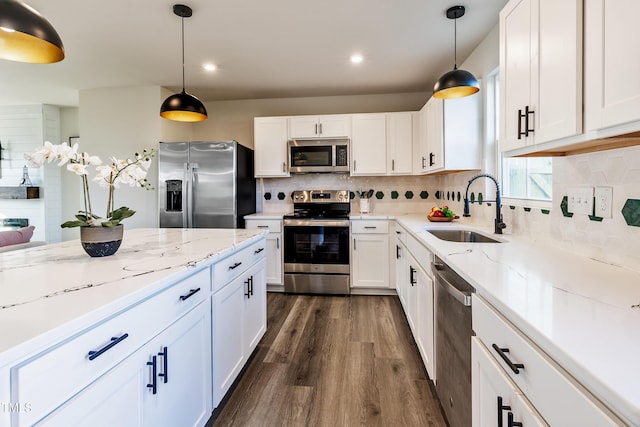 kitchen with decorative light fixtures, stainless steel appliances, white cabinetry, and sink