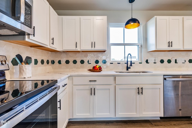 kitchen with sink, white cabinets, decorative light fixtures, and appliances with stainless steel finishes