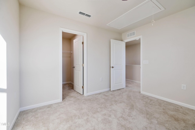 unfurnished bedroom with light colored carpet, a spacious closet, and a closet