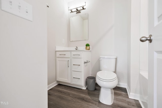 bathroom with a bath, wood-type flooring, vanity, and toilet