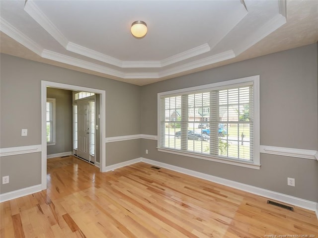 spare room featuring hardwood / wood-style floors, crown molding, and a tray ceiling