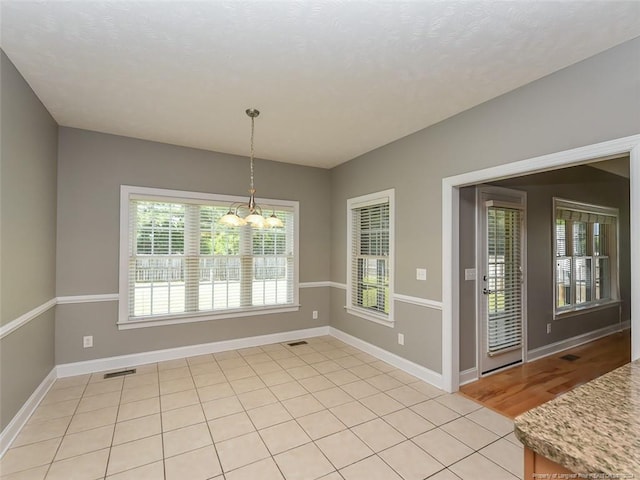 unfurnished dining area with a notable chandelier and light tile patterned flooring