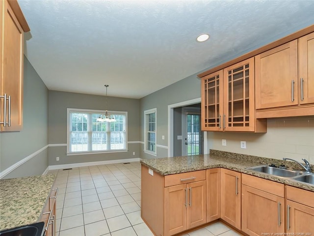 kitchen featuring decorative backsplash, light stone countertops, light tile patterned floors, and sink