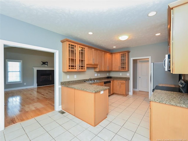 kitchen with kitchen peninsula, sink, light tile patterned floors, and stainless steel appliances