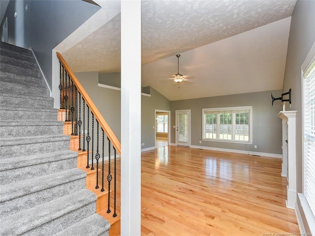 stairway with wood-type flooring, a textured ceiling, high vaulted ceiling, and ceiling fan