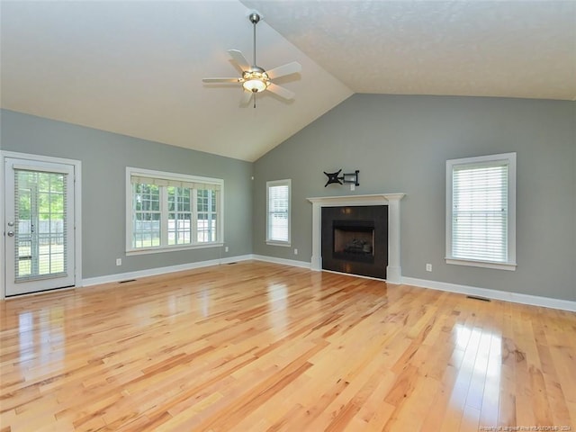 unfurnished living room featuring vaulted ceiling, light hardwood / wood-style flooring, ceiling fan, and a healthy amount of sunlight