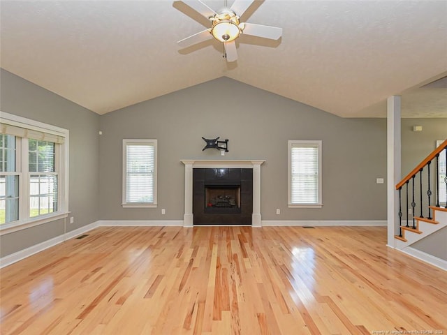 unfurnished living room with a fireplace, light wood-type flooring, vaulted ceiling, and ceiling fan