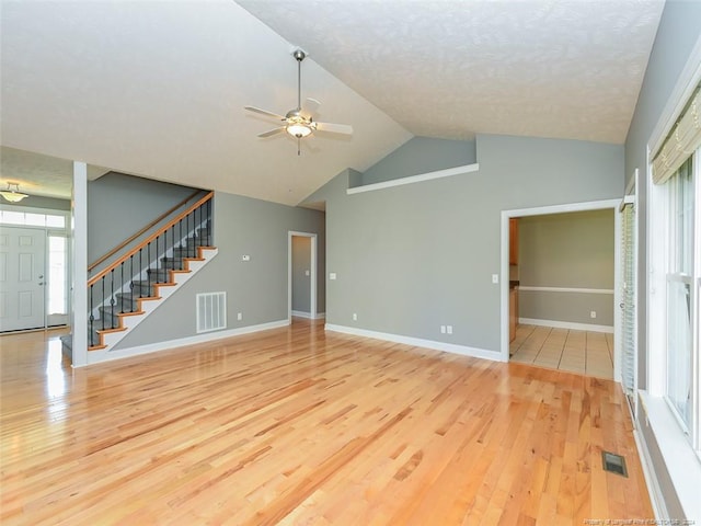 unfurnished living room with ceiling fan, vaulted ceiling, a textured ceiling, and light hardwood / wood-style flooring