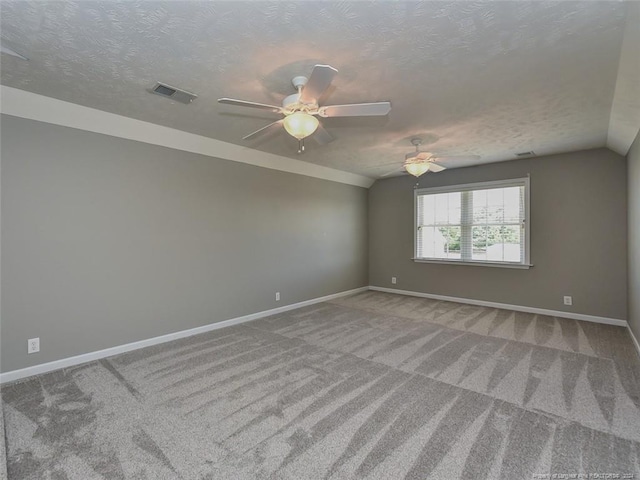 empty room featuring carpet flooring, ceiling fan, vaulted ceiling, and a textured ceiling