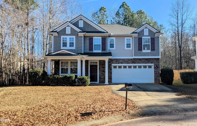 view of front of home with driveway, stone siding, roof with shingles, an attached garage, and a porch