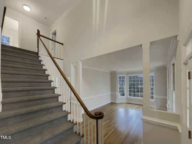 staircase featuring hardwood / wood-style flooring, ornate columns, and ornamental molding