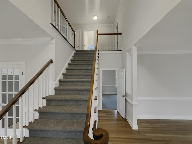 stairs featuring wood-type flooring and crown molding