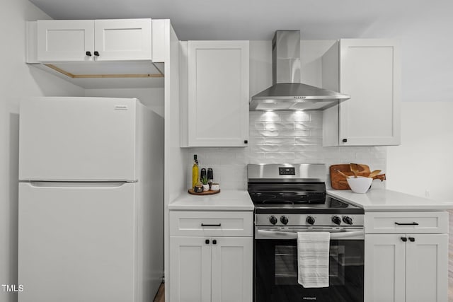 kitchen featuring white cabinetry, wall chimney range hood, stainless steel range with electric cooktop, and white fridge