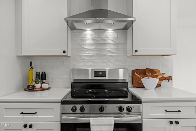 kitchen with stainless steel range with electric stovetop, white cabinetry, and wall chimney exhaust hood