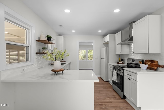 kitchen with wall chimney range hood, white cabinetry, electric range, decorative backsplash, and white fridge