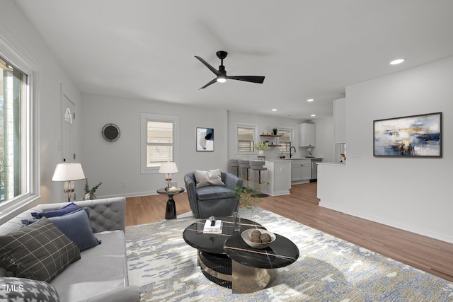 living room with sink, plenty of natural light, ceiling fan, and light wood-type flooring