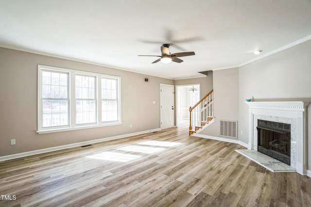 unfurnished living room featuring ceiling fan, a fireplace, crown molding, and light hardwood / wood-style flooring