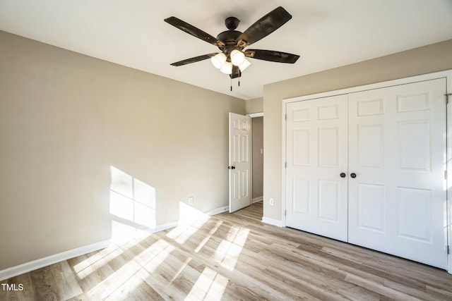 unfurnished bedroom with ceiling fan, light wood-type flooring, and a closet